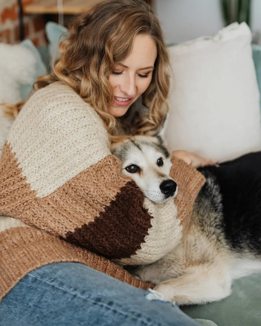 Frau kuschelt auf dem Sofa mit ihrem Hund